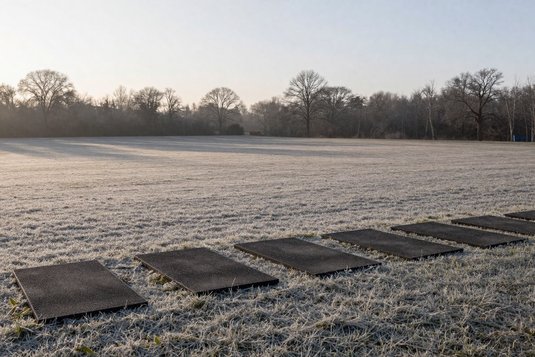 Outdoor driving range in late winter light, frost on the ground and bare trees